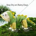 Small white dog wearing a green dinosaur hooded raincoat with yellow spikes and a tail, standing on moss in the rain