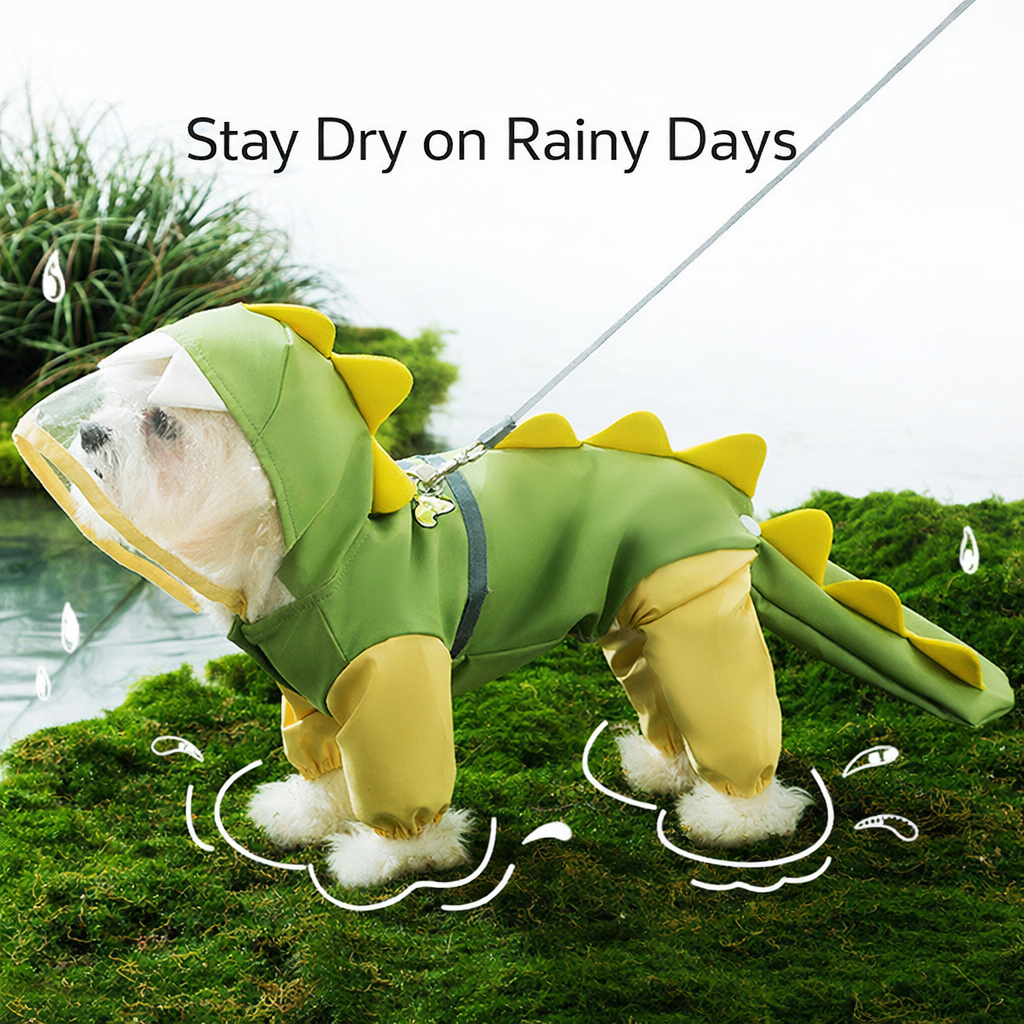 Small white dog wearing a green dinosaur hooded raincoat with yellow spikes and a tail, standing on moss in the rain